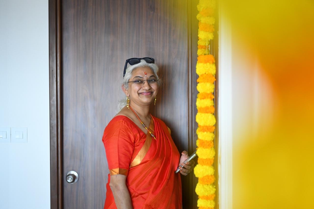 Sowmya Ayyar smiling in a red sari beside a marigold garland