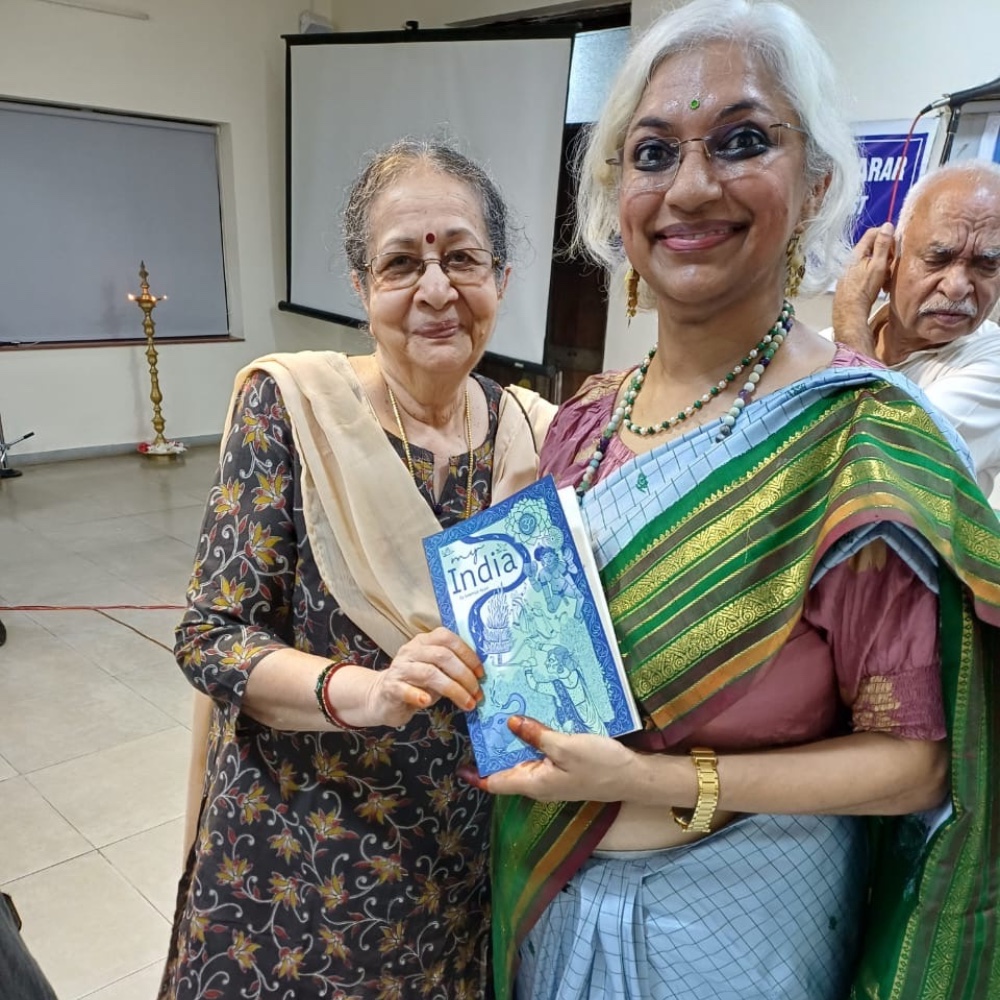 Sowmya with an elder guest at the My India launch, both holding the book