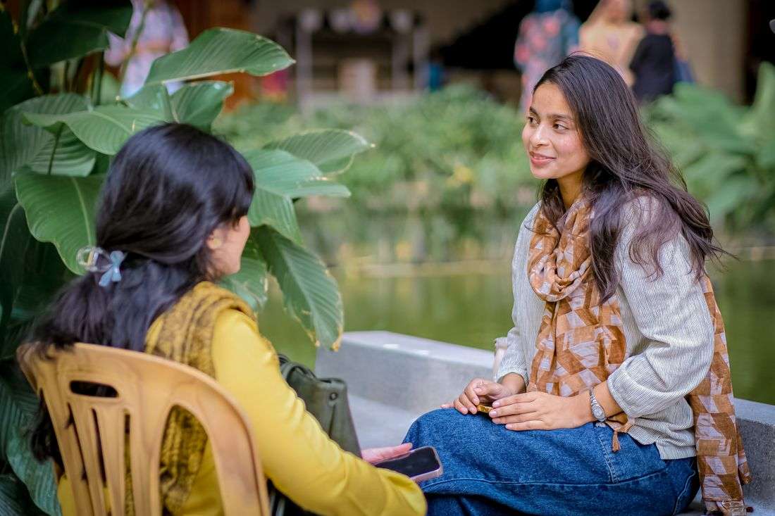 Two women in an unhurried mentoring conversation in a garden courtyard