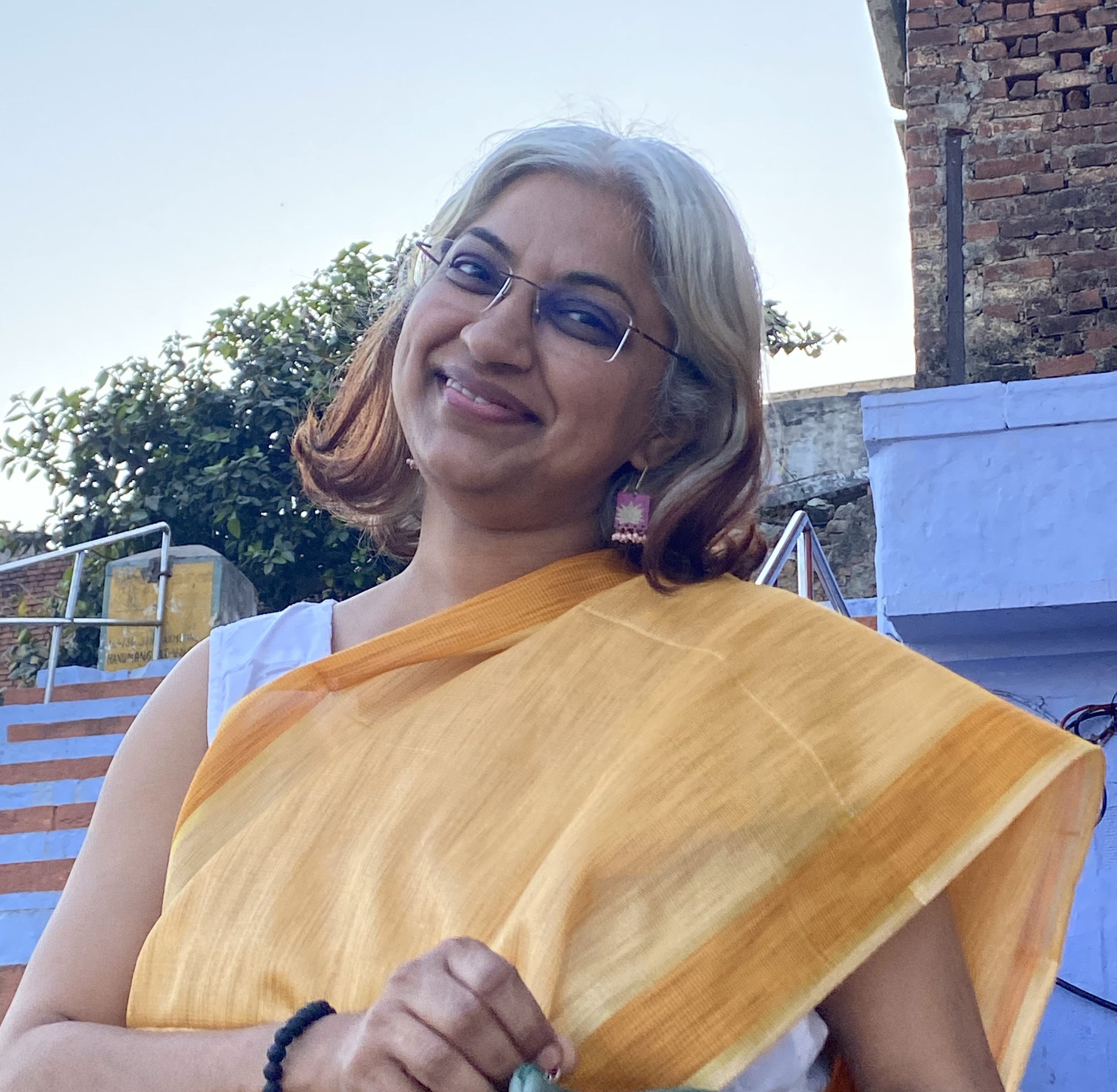 Sowmya Ayyar smiling outdoors in a yellow sari