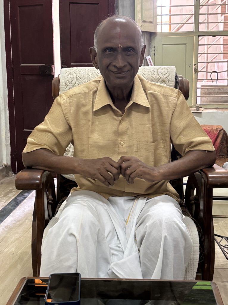 The retired headmaster wearing a light-colored shirt and a traditional dhoti, regaling me with his thoughts on Andal.
